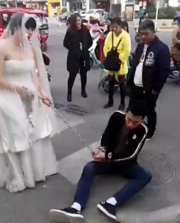 新娘穿婚纱街头用铁链捆上新郎去完婚