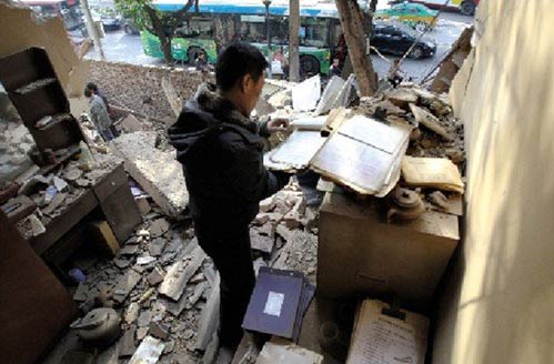 在一个被强拆的化工材料商店，老板刘先生在残垣断壁里找到了账本。本报记者 黄利健 摄