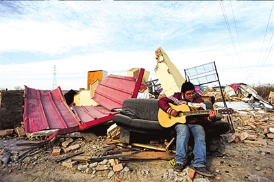 陕西学生李阳从废墟中挖出一把吉他，试了试，还能弹。