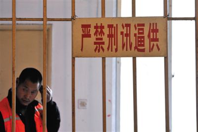 2014年3月18日，四川省成都市，一犯罪嫌疑人在“严禁刑讯逼供”的标牌下接受审讯。图/CFP