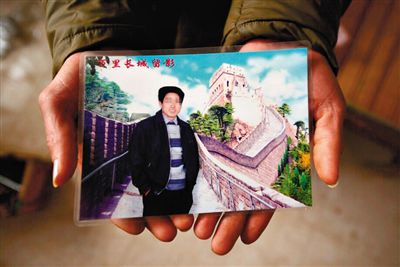 尹小枫的儿子捧着父亲生前的照片。