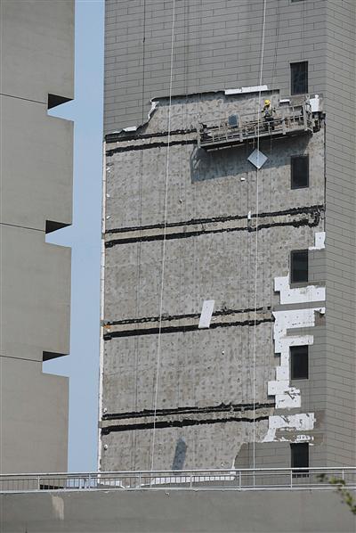 7月6日15时左右，顺义区悦君家园8号楼，工人在清理事发外墙上的保温层。 新京报记者 朱骏 摄