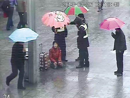 图为民警、综管队员为周某撑伞劝解的监控截图。