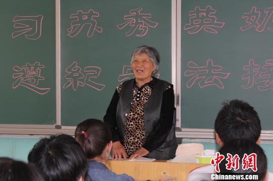 苏秀英老人把《中学生法律知识读本》、《廉洁教育》发到学生们的手中。 张本宝 摄